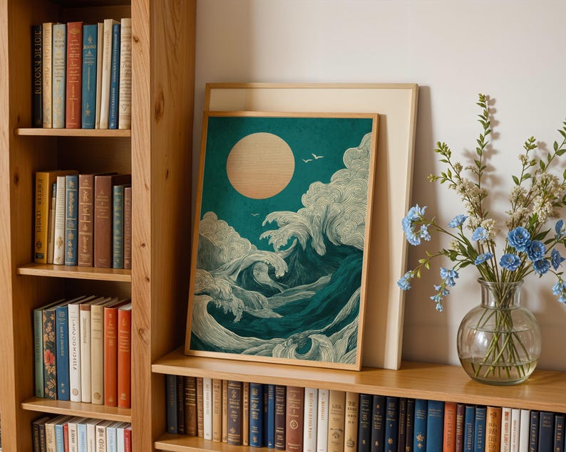 K&ouml;nnte beinhalten: Ein gerahmter Kunstdruck, der eine stilisierte Meereslandschaft mit einer gro&szlig;en Sonne und tosenden Wellen in T&uuml;rkis, Wei&szlig; und Dunkelblau zeigt. Das Kunstwerk wird auf einem Holzregal mit einem B&uuml;cherregal und einer Vase mit blauen Blumen ausgestellt.