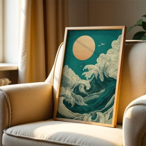 K&ouml;nnte beinhalten: Ein gerahmter Kunstdruck, der eine stilisierte Ozeanwellenszene mit einer gro&szlig;en Sonne und V&ouml;geln zeigt. Das Kunstwerk weist teal- und cremefarbene Farben mit einem Holzrahmen auf. Der Druck wird auf einem beigen Sessel pr&auml;sentiert.