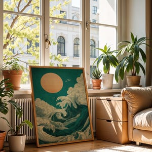 K&ouml;nnte beinhalten: Ein gerahmter Kunstdruck mit stilisierten Meereswellen, einer gro&szlig;en Sonne und V&ouml;geln vor einem teal-farbenen Hintergrund. Das Kunstwerk wird in einem Raum mit Topfpflanzen und einem Fenster mit Blick auf eine Stadt ausgestellt.