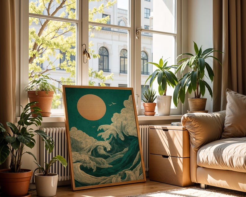 K&ouml;nnte beinhalten: Ein gerahmter Kunstdruck mit stilisierten Meereswellen, einer gro&szlig;en Sonne und V&ouml;geln vor einem teal-farbenen Hintergrund. Das Kunstwerk wird in einem Raum mit Topfpflanzen und einem Fenster mit Blick auf eine Stadt ausgestellt.