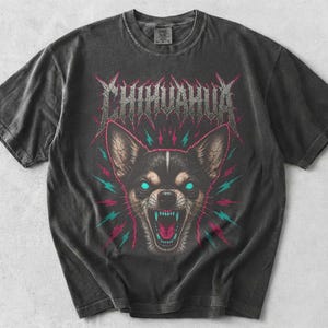 May include: A charcoal gray short-sleeve t-shirt featuring a graphic of a snarling chihuahua with glowing cyan eyes and teeth. Above the dog, the word CHIHUAHUA is printed in a jagged, metallic-style font. The design includes red and cyan lightning bolts.