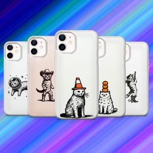 May include: A collection of five white phone cases with unique black and white cat illustrations. The designs include a cat in a space suit, a cowboy cat, a cat with a traffic cone hat, a cat with pumpkins, and a cat with a gun.