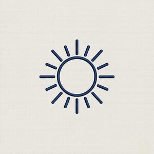 May include: A navy blue embroidered sun design on a cream-colored fabric. The sun has a circular center with radiating lines extending outward, creating a stylized sunburst effect. The embroidery is detailed and the design is centered.
