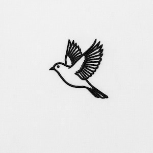 May include: An embroidered design of a bird in flight, rendered in black thread on a white background. The bird's wings are outstretched, with detailed feathering. The image is simple yet elegant, focusing on the bird's form.