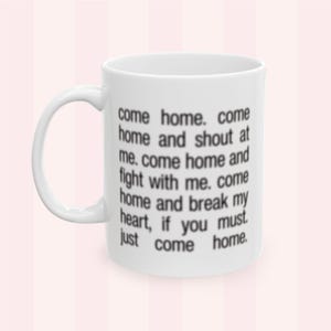 Könnte beinhalten: Weißer Keramikbecher mit gebogenem Henkel. Der Becher hat einen schwarzen Text, der lautet: "come home. come home and shout at me. come home and fight with me. come home and break my heart, if you must. just come home."