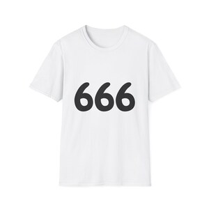 Puede incluir: Una camiseta blanca de manga corta con el número 666 impreso en una fuente sans-serif negra, negrita y redondeada en el centro del pecho. La prenda tiene un cuello redondo estándar y un dobladillo recto, confeccionada en tela blanca lisa.