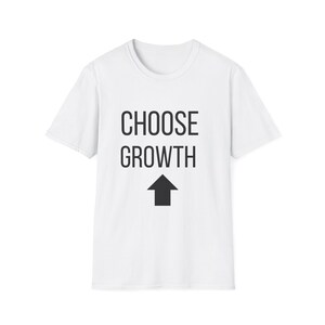 Puede incluir: Camiseta blanca con las palabras "CHOOSE GROWTH" en letras negras y una flecha negra que apunta hacia arriba. La camiseta tiene cuello redondo y mangas cortas.