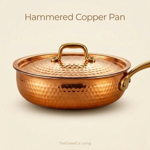 May include: A copper hammered pan with a lid and handle. The pan has a hammered texture and a gold-colored handle. The text "Hammered Copper Pan" is at the top of the image. The ElatedCo Living is at the bottom.