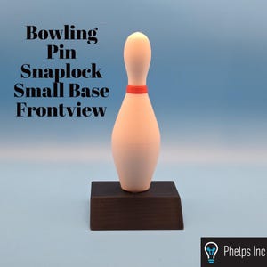 Pode incluir: Um pino de boliche com uma base pequena, vista frontal. O pino é branco sujo com uma faixa vermelha ao redor do pescoço. É montado em uma base retangular marrom escuro. O texto na imagem diz "Bowling Pin Snaplock Small Base Frontview."