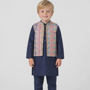 May include: A dark blue long-sleeved tunic and matching trousers paired with a sleeveless vest featuring a vibrant, multi-colored chevron and geometric pattern. The vest has a front button closure and a mandarin collar, worn over the solid navy outfit.