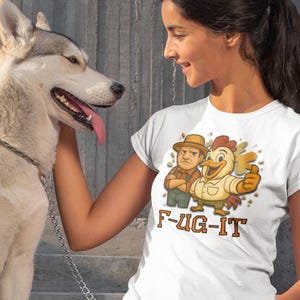 May include: A white t-shirt with a cartoon of a farmer and a chicken, and the text "F-UG-IT". The farmer has crossed arms and the chicken gives a thumbs up. A woman is wearing the shirt and petting a husky dog.