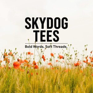 May include: Image features the text "SKYDOG TEES" in bold black letters above the tagline "Bold Words. Soft Threads." A field of wheat and red poppies fills the foreground against a light sky.