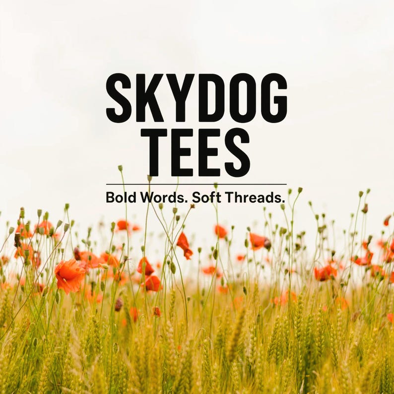 May include: Image features the text "SKYDOG TEES" in bold black letters above the tagline "Bold Words. Soft Threads." A field of wheat and red poppies fills the foreground against a light sky.