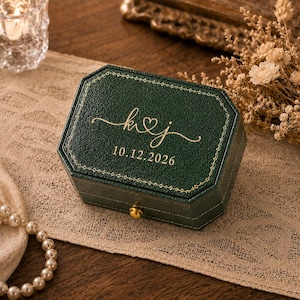 May include: A dark green, octagonal jewelry box with a textured finish and gold-colored trim. The lid features gold lettering that reads k heart j and the date 10.12.2026. A small gold-colored circular latch is centered on the front of the box.