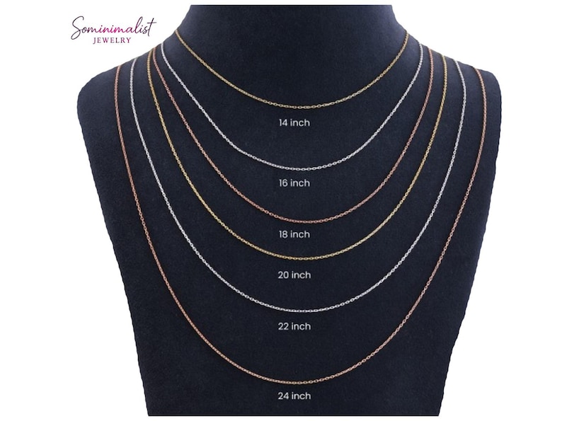 May include: A display of six delicate necklaces in varying lengths, ranging from 35.5 cm to 61 cm. The necklaces are gold, silver, and rose gold, showcasing different chain styles. The lengths are labeled on the display. The brand name "Sominimalist Jewelry" is visible.