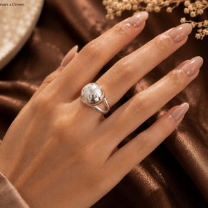 May include: A polished silver ring featuring a large, smooth, spherical ball centrepiece on a simple band. The ring is marked with the text 925SilverCrownIn and the phrase Where Elegance Wears a Crown, accompanied by a small crown icon above the text.