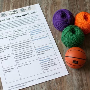 May include: A printed yarn match guide with the text "NBA Team Colors" next to four yarn balls in purple, green, and orange, and a small orange basketball. The guide lists yarn brands and retailers.