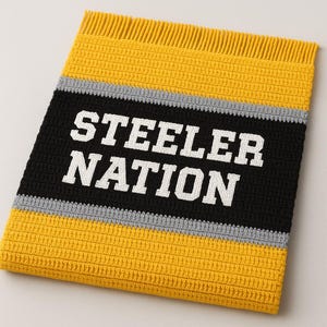 May include: A handmade crochet blanket in yellow, black, and gray, featuring the text "STEELER NATION" in white. The blanket has a fringed edge and a striped design, perfect for sports fans.