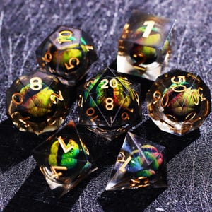May include: Set of seven polyhedral dice with a clear resin exterior and colorful, iridescent interiors. The numbers are gold. The dice are for tabletop role-playing games.