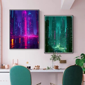 May include: Two framed art prints depicting futuristic cityscapes. The left print showcases a vibrant neon-lit city with pink and purple hues, while the right print features a teal and green cityscape. Both prints are framed in black and hang on a pink wall.