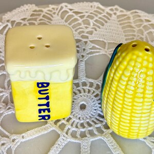 May include: A pair of ceramic salt and pepper shakers. One is shaped like a stick of butter with the word "BUTTER" in blue. The other is shaped like an ear of corn with yellow kernels and green and blue husks.