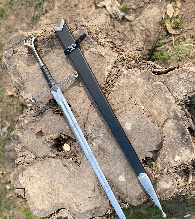 May include: A silver and black sword with a decorative hilt and crossguard, lying on a tree stump. The sword has a long, straight blade and is next to a black sheath. The hilt features gold and silver accents.