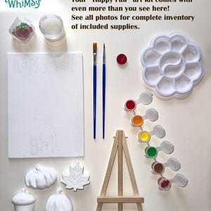 May include: A Happy Fall art kit containing a white canvas with the text happy fall y'all, two paintbrushes, a flower-shaped palette, a strip of six paint pots, a wooden easel, and four white ceramic shapes: two pumpkins, a leaf, and an acorn.