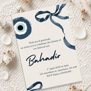 May include: Invitation card with a watercolor design. The card features a blue eye symbol and a blue ribbon. Text on the card reads "With Joy & gratitude, we invite you to celebrate the Sünnet of our beloved son Bahadir".