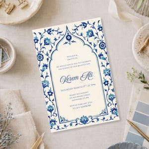 May include: A rectangular invitation card featuring a cream background with a blue and white floral border in an Iznik-inspired style. The center displays an arched frame containing text that reads: With Joy & Gratitude, We Would Invite You To Celebrate The Sunnet Of Our Beloved Son, Kerem Ali, Saturday March 13th At 5pm, Kismet Restaurant, 123 Anywhere Street, Anywhere 123 456, RSVP By February 27th To Sev 123456789.