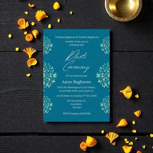 May include: A teal invitation card with floral accents and text inviting guests to a ceremony. The card is surrounded by yellow flower petals and a small gold bowl on a dark wooden surface.