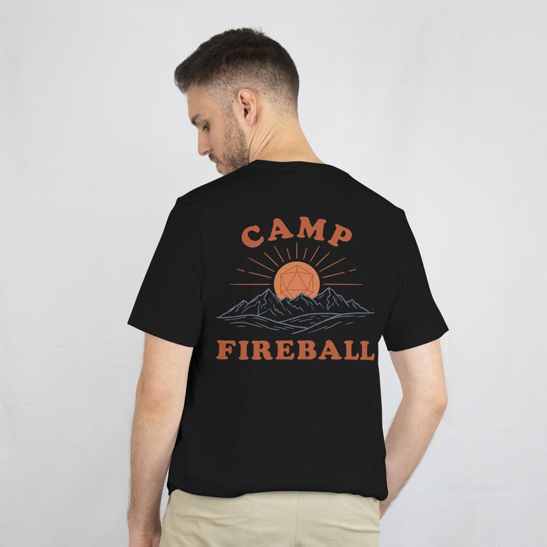 K&ouml;nnte beinhalten: Schwarzes T-Shirt mit einem grafischen Design auf der R&uuml;ckseite. Das Design zeigt die Worte "CAMP FIREBALL" in Orange, mit einer Sonne und einer Bergillustration &uuml;ber dem Text. Das Shirt ist aus weichem Material.
