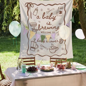 May include: A baby shower scene with a banner that reads "a baby is brewing welcome to a baby shower." The banner has coffee-themed illustrations. A table is set with food, drinks, and decorations, including balloons and a string of colorful flags.