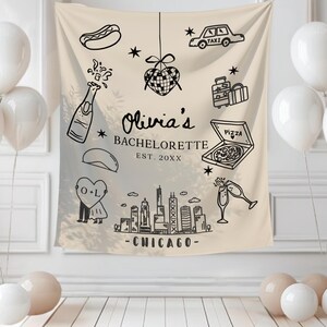 May include: A beige fabric backdrop with black line art illustrations for a bachelorette party. The design includes a hot dog, champagne bottle, taxi, luggage, pizza, and Chicago skyline. White balloons are arranged around the backdrop.