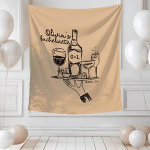 K&ouml;nnte beinhalten: Beige Wandbehang mit einer schwarzen Illustration einer Weinflasche, Gl&auml;sern und einer K&auml;seplatte. Der Text lautet "Olivia's bachelorette" und "NAPA, CA". Wei&szlig;e Ballons sind im Vordergrund.
