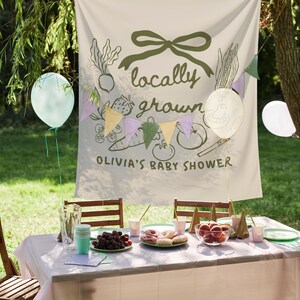Może przedstawiać: Scena baby shower na świeżym powietrzu ze stołem przygotowanym na przyjęcie. Banner głosi "locally grown" z ilustracjami warzyw. Balony i girlandy zdobią scenę. St&oacute;ł jest zastawiony jedzeniem i napojami.