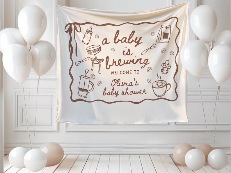May include: A white banner with brown illustrations and text that reads "a baby is brewing" and "Welcome to Olivia's baby shower." The banner is surrounded by white balloons and beige orbs.