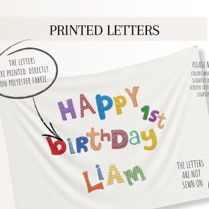 May include: A white polyester fabric banner featuring the colorful printed text HAPPY 1st BIRTHDAY LIAM. The letters have various patterns and colors. Text on the banner states: THE LETTERS ARE PRINTED DIRECTLY ON POLYESTER FABRIC and THE LETTERS ARE NOT SEWN ON.