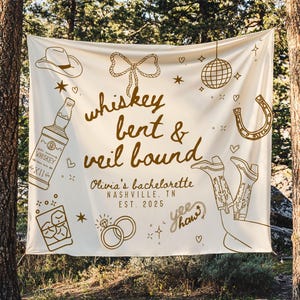 May include: Cream-colored banner with brown illustrations and text for a bachelorette party. The banner includes drawings of a cowboy hat, whiskey bottle, disco ball, horseshoe, cowboy boots, and rings. Text reads "whiskey bent & veil bound" and "Olivia's bachelorette Nashville, TN EST. 2025."