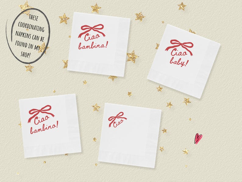 May include: White square napkins with a red bow and the words "Ciao bambina!" and "Ciao baby!" printed on them. The napkins are scattered on a cream-colored surface with gold star-shaped confetti.