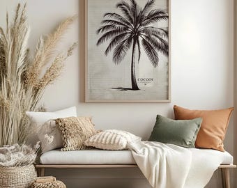 May include: A framed black and white palm tree print with the word "COCOOS" at the bottom. The print hangs above a white bench with decorative pillows and a blanket. A woven basket and dried plants are in the foreground.