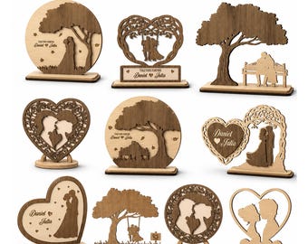 May include: A collection of 10 laser-cut wooden decorative stands featuring silhouettes of couples, trees, and heart shapes. The designs include text reading "TOGETHER FOREVER" and "Daniel & Julia" with specified material thicknesses of 3mm and 4mm.