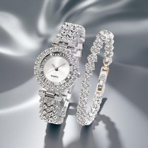 May include: A silver-toned quartz watch and matching bracelet set. The watch features a round face with Roman numeral hour markers and a bezel encrusted with sparkling crystals. The bracelet has a similar design, with a series of crystal-studded links.
