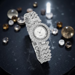 May include: Silver-toned quartz watch with a white face and Roman numeral hour markers. The watch is encrusted with clear crystals around the bezel and on the band. The word "QUARTZ" is printed on the watch face.