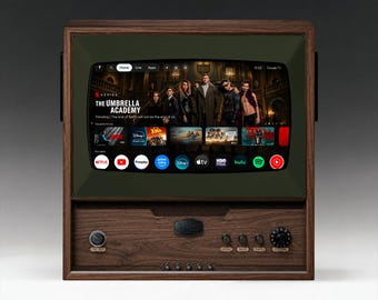 Könnte beinhalten: Ein dunkelbraunes Fernsehgerät mit einem retro-inspirierten Rahmen und einem dunkelgrünen Bildschirmrand. Das Display zeigt eine Google TV-Oberfläche mit The Umbrella Academy und verschiedenen App-Symbolen. Die Frontblende enthält Drehregler.