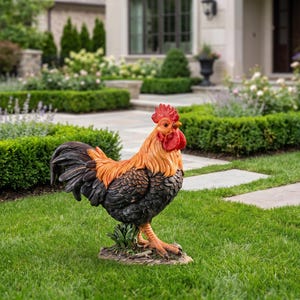 May include: A decorative rooster statue featuring a vibrant red comb and wattle, a bright orange neck, and dark charcoal-colored feathers on the body and tail. The figure stands on a small, textured base with green foliage details.