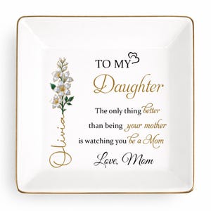 May include: A white square trinket dish with a gold rim. The dish features a floral design and the text "TO MY Daughter" in gold script. Additional text reads "The only thing better than being your mother is watching you be a Mom. Love, Mom."