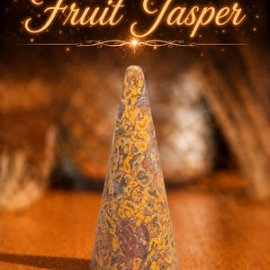 K&ouml;nnte beinhalten: Ein kegelf&ouml;rmiges Objekt aus Fruit-Jasper-Stein mit einem gesprenkelten Muster in Gelb, Braun und Dunkelrot. Der Text "Fruit Jasper" erscheint in einer leuchtenden Schreibschrift &uuml;ber dem Steinobjekt, das eine glatte Oberfl&auml;che aufweist.
