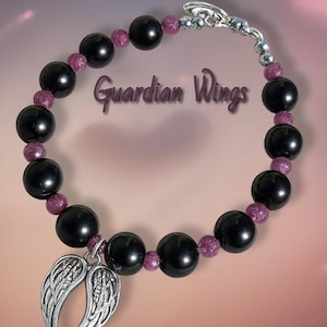 May include: A beaded bracelet featuring black and purple beads with a silver-toned charm of angel wings. The bracelet has a silver clasp and the words "Guardian Wings" are written on the image.