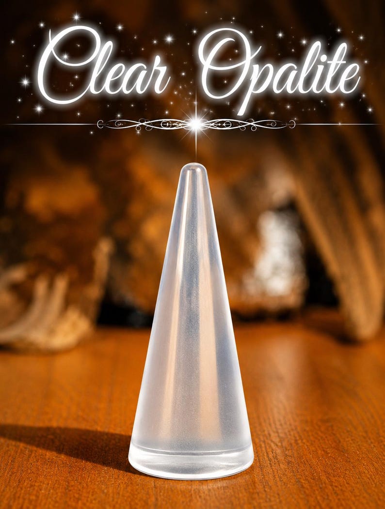 K&ouml;nnte beinhalten: Ein durchscheinender, kegelf&ouml;rmiger Ringst&auml;nder aus klarem Opalit. Das Objekt hat eine glatte, spitz zulaufende Oberfl&auml;che und einen runden Boden. Der Text "Clear Opalite" steht in wei&szlig;er Schreibschrift &uuml;ber dem Objekt mit Sternakzenten.