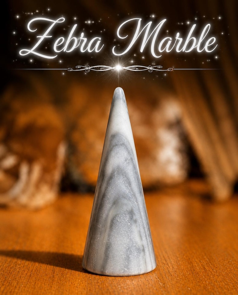K&ouml;nnte beinhalten: Ein kegelf&ouml;rmiges Objekt aus Zebramarmor mit einer glatten, polierten Oberfl&auml;che, die wirbelnde graue und wei&szlig;e Muster aufweist. Der Text "Zebra Marble" ist in einer wei&szlig;en Schreibschrift &uuml;ber dem Objekt dargestellt, akzentuiert durch kleine sternartige Funken.